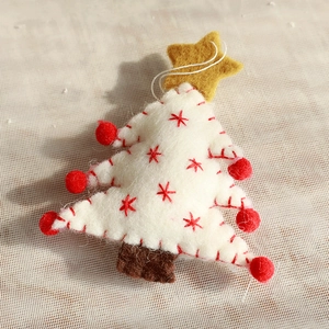 Close-up of handmade white wool felt Christmas tree ornament with red star embroidery