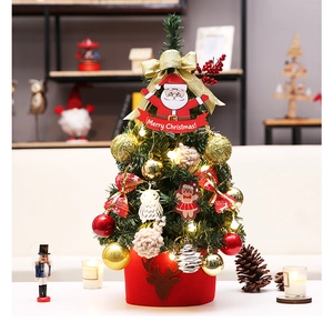 Detail of a desktop Christmas tree with LED lights, golden bows, and a red felt base