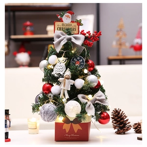 Close-up of a tabletop Christmas tree with red ornaments, LED lights, and gift box base