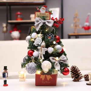 Mini tabletop Christmas tree with red berries, owls, and LED lights on a red gift box