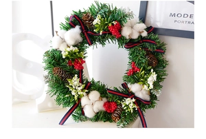 Detail of Christmas wreath with red berries, cotton bolls and pine cones on green pine needles