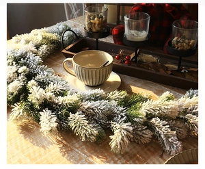 Close-up of 1.8m snow-flocked pine garland on a rustic table with winter decorations