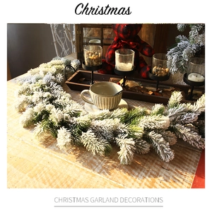 Close-up of 1.8m snow-flocked Christmas garland on a wooden table with festive decor