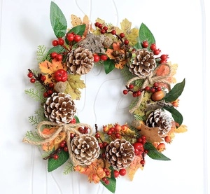 Close-up of autumn wreath with maple leaves, pine cones, pumpkins and burlap bow detail