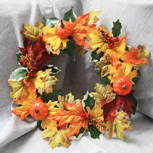 Detailed close-up of Halloween wreath with maple leaves, pumpkins, and red berries