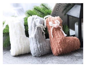 Détail de chaussettes de Noël tricotées avec des nœuds blancs et des pompons en peluche