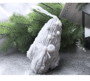 Détail d'un pendentif de Noël en tricot gris avec des pompons blancs et un nœud doux