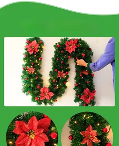 Detalle de guirnalda navideña con flores de nochebuena rojas y luces LED cálidas