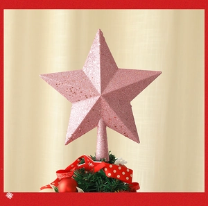 Estrella de Navidad rosa con purpurina en la copa del árbol con cintas rojas y bolas