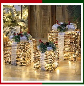 Close-up of three lighted wicker Christmas gift boxes with warm LED and pine decorations