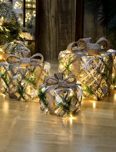 Close-up of three burlap Christmas gift boxes with bows and warm LED lights