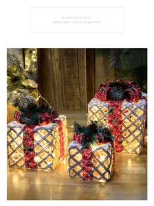 Close-up of glowing Christmas gift box set with red ribbons and snowy pine cones