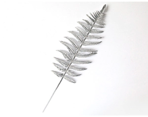 Close-up of artificial silver glitter fern leaf branch for festive Christmas decoration