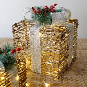 Golden Christmas gift box set with warm LED lights and silver bow on wood table