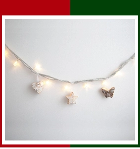 Macro detail of wooden heart and star ornaments on rustic LED fairy light string