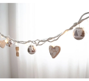 Macro shot of rustic Christmas string lights with wooden hearts and Nordic tree ornaments