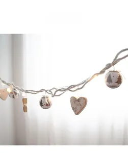 Close-up of wooden heart pendants and glowing globes on rustic jute rope decor