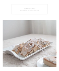 Close-up of wooden heart and star ornaments with white ribbons on a white ceramic plate