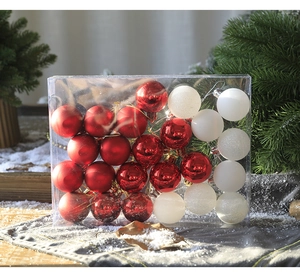 Detail of red and white Christmas ball ornaments in a transparent box on snowy wood