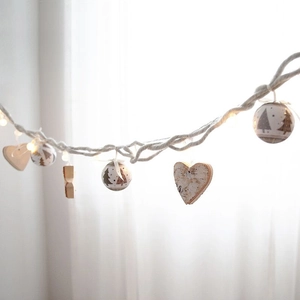 Wooden heart and Christmas tree ornaments on warm white LED string lights for home decor