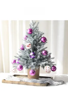 Détail d'un sapin de Noël floqué avec des boules décorées violettes dans un pot en céramique