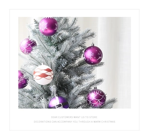 Gros plan de boules de Noël violettes et blanches suspendues à un sapin argenté givré