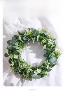 Detail of Nordic eucalyptus wreath with white flowers on soft white fabric