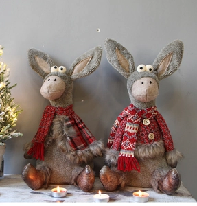 Close-up of cute donkey Christmas dolls with red scarves on a cozy wooden table setup