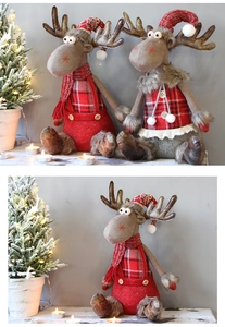 Close-up of reindeer plush dolls with red plaid outfits and knitted hats on a table