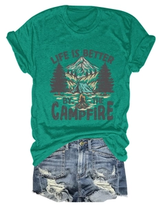 Flat lay of a teal camping t-shirt with campfire graphic and distressed denim shorts