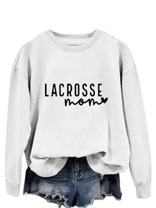 White long-sleeved Lacrosse Mom sweatshirt with heart graphic and denim shorts detail