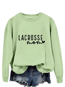 Detail of light green sweatshirt featuring black Lacrosse Mom text and heart print