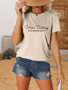 Close-up of Wine Tasting Is My Favorite Sport text on apricot t-shirt and ripped denim shorts