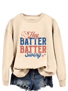 Détail du sweat beige à col rond avec motif baseball et short en jean effiloché
