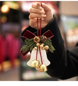 Gros plan d'un pendentif cloche de Noël avec nœud en velours rouge et pommes de pin