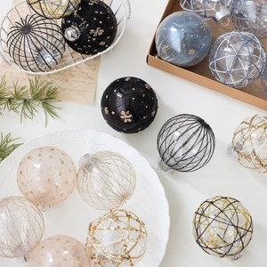8cm bemaltes Christbaumkugeln Set in Schwarz und Gold mit Pailletten auf einem Teller