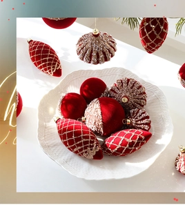 Close-up of red velvet Christmas ornaments with gold embroidery and beads on a ceramic plate