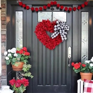 Red heart fabric wreath with buffalo plaid bow hanging on a black wooden door