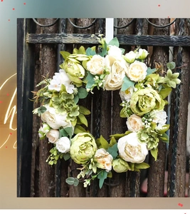 Couronne de pivoines crème et feuilles vertes sur une porte en bois de style rustique