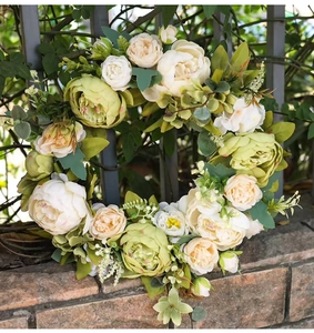 Vue détaillée d'une couronne de pivoines artificielles blanches sur un mur de briques