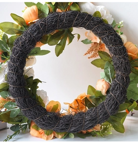 Macro shot of artificial peony wreath with autumn leaves and rustic vine base