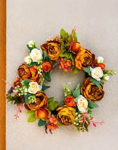 Gros plan d'une couronne de pivoines artificielles avec fleurs orange et feuilles vertes