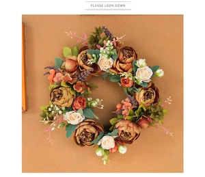 Detail of vintage autumn peony wreath with silk orange blossoms on a textured wall