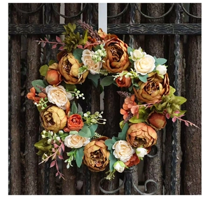 Detailed view of autumn peony wreath with orange flowers and berries on a dark wooden fence
