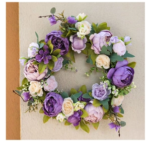 Detailed view of artificial peony wreath with purple and cream flowers on a wall