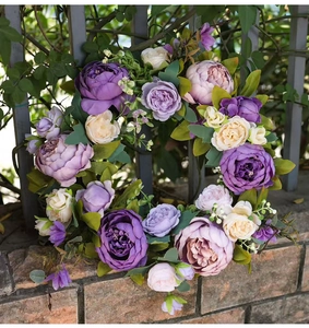 Detailed close-up of handmade purple peony and rose wreath hanging on a metal fence