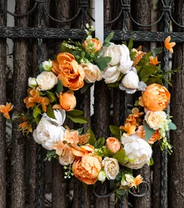 Dettaglio di peonie artificiali crema e arancione su una ghirlanda decorativa per casa