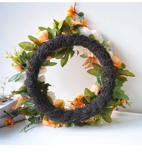 Detailansicht künstlicher Pfingstrosenkranz mit orangen Stoffblumen auf Rattankranz
