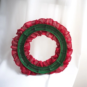 Detail of DIY wreath base with green plastic frame and red burlap mesh ruffle trim