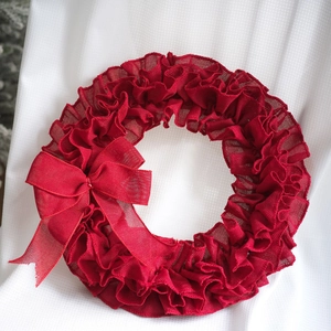 Close-up of red burlap festive wreath with layered mesh texture and side bow detail